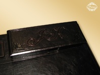 Piórnik skórzany będący fragmentem podkładu na biurko, ozdobiony tłoczeniami i ozdobnymi inicjałami właściciela.